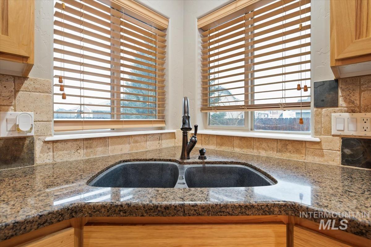 Kitchen with tasteful backsplash and dark stone counters