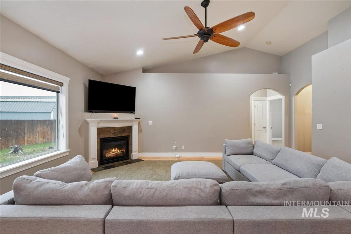 Living area with lofted ceiling, recessed lighting, arched walkways, a fireplace with flush hearth, and ceiling fan