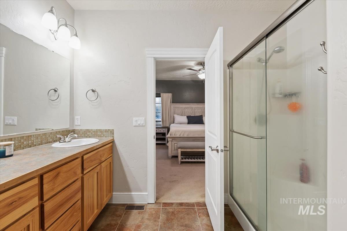 Full bath featuring ensuite bath, a shower stall, vanity, and dark tile patterned floors