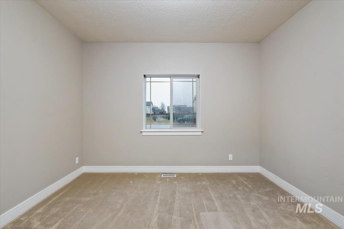 Spare room with a textured ceiling and light carpet