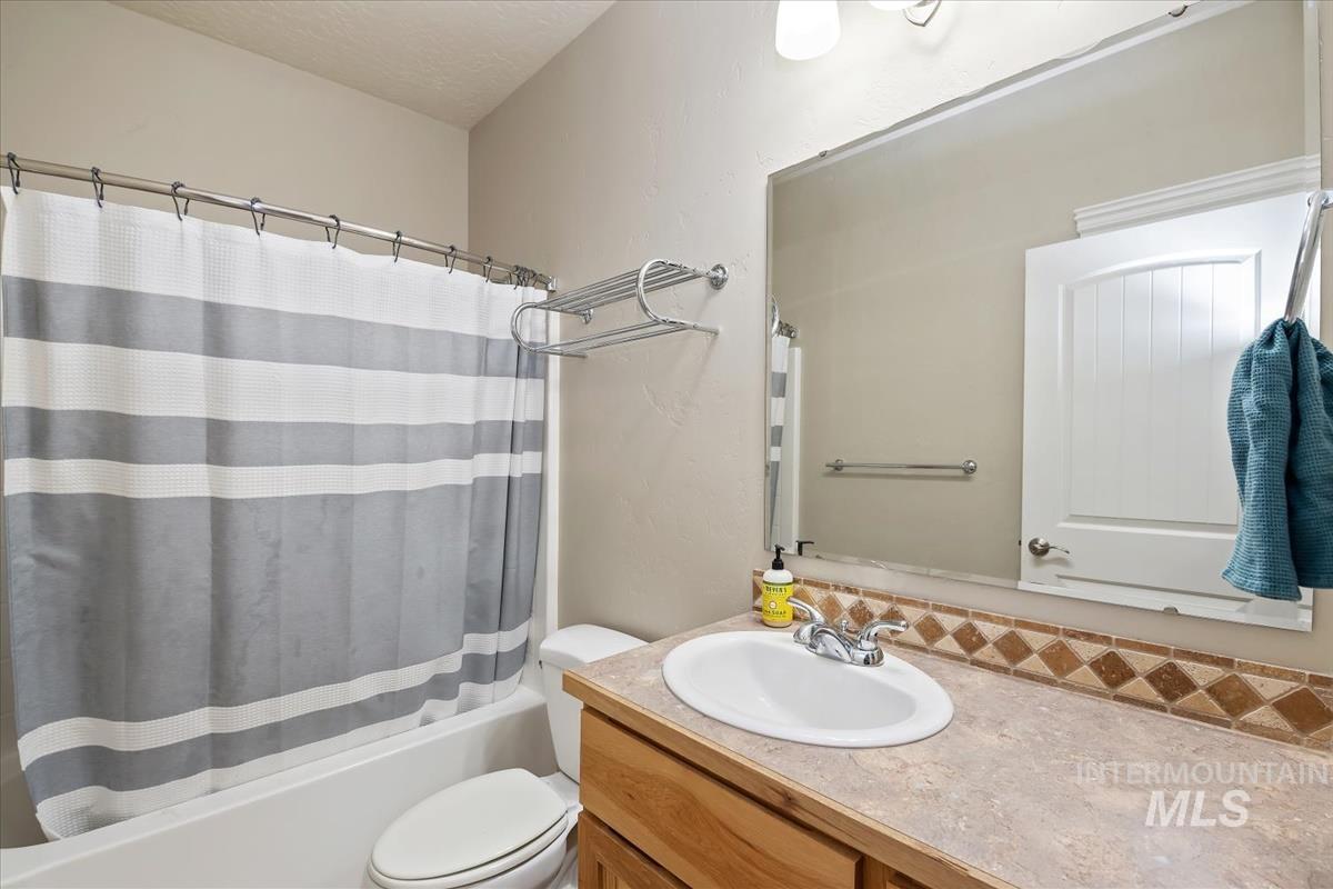 Full bathroom featuring shower / bath combination with curtain and vanity