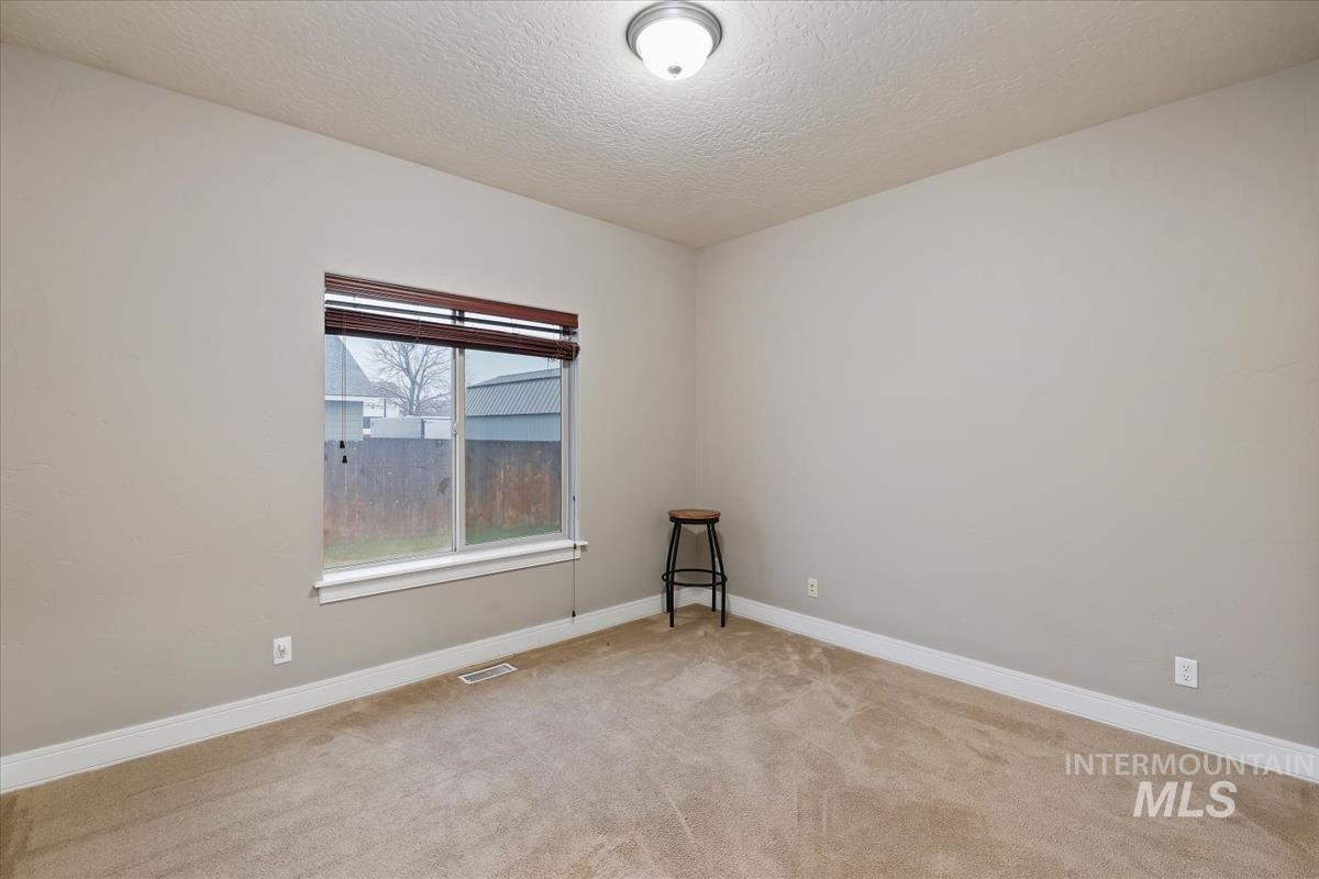 Unfurnished room featuring a textured ceiling and light colored carpet