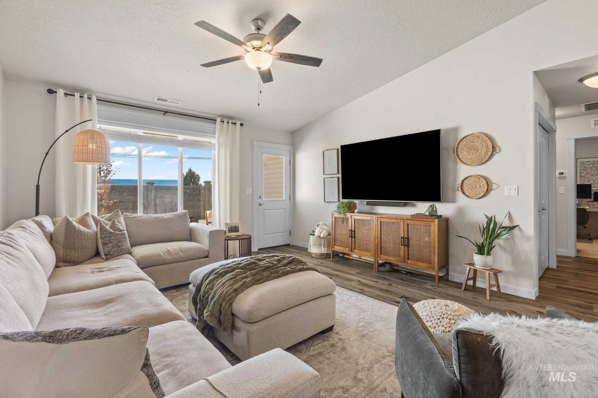 Living area with vaulted ceiling, wood finished floors, a ceiling fan, and a textured ceiling