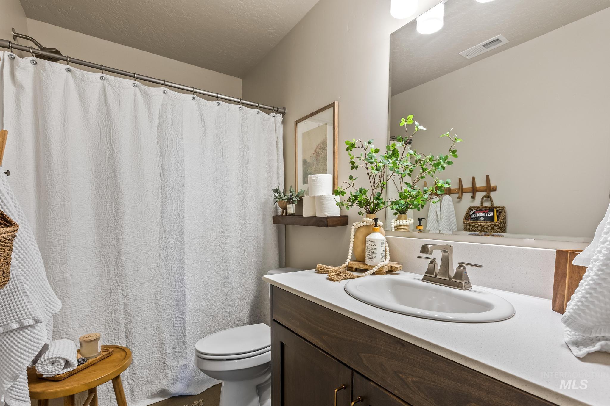 Full bathroom featuring vanity, curtained shower, and a textured ceiling