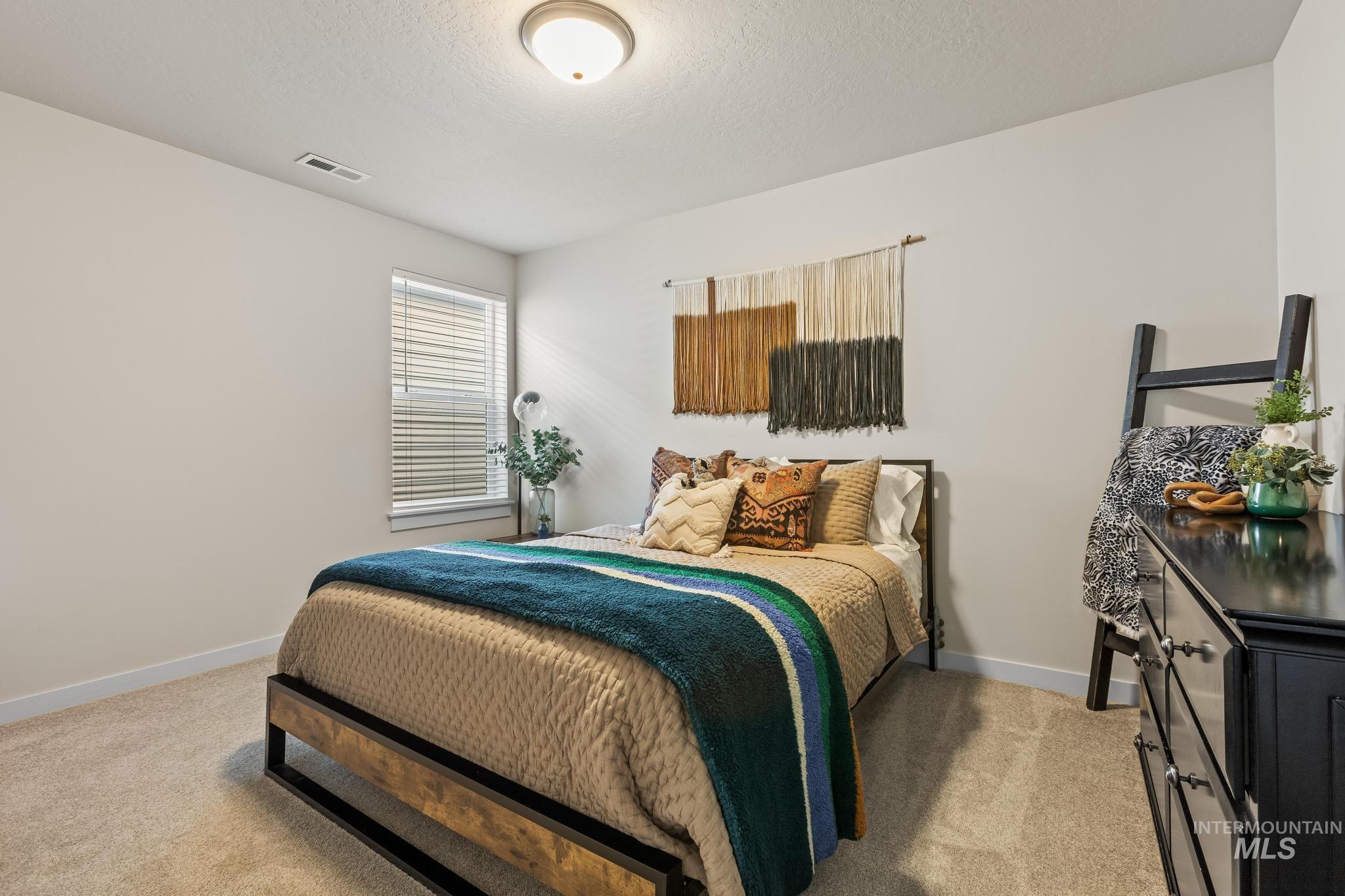 Bedroom featuring light colored carpet and a textured ceiling