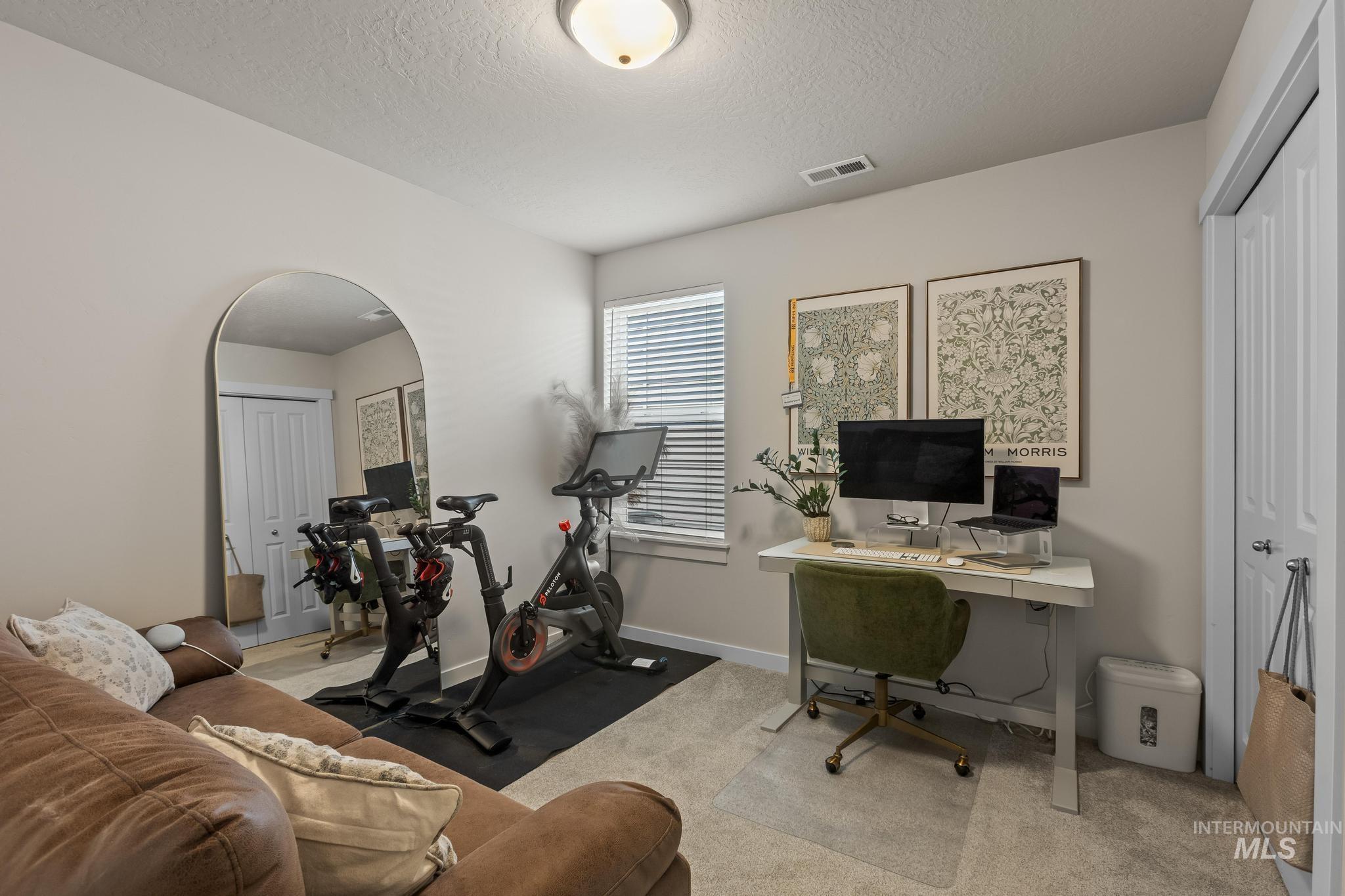 Office space with a textured ceiling, arched walkways, and light colored carpet