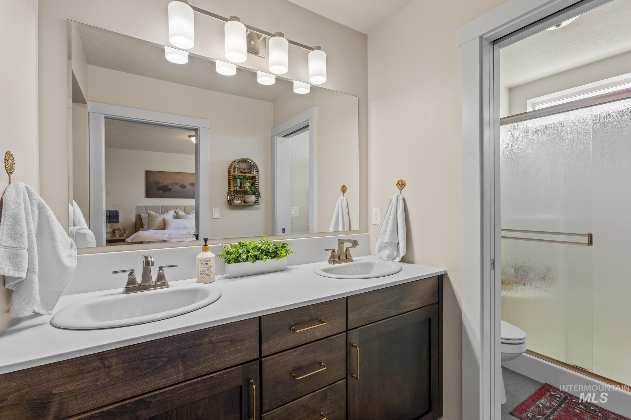 Bathroom featuring double vanity, a stall shower, and connected bathroom