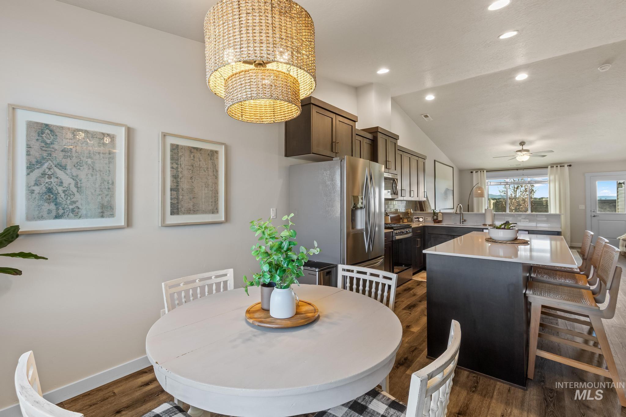 Dining space with dark wood-style floors, lofted ceiling, a ceiling fan, recessed lighting, and a chandelier