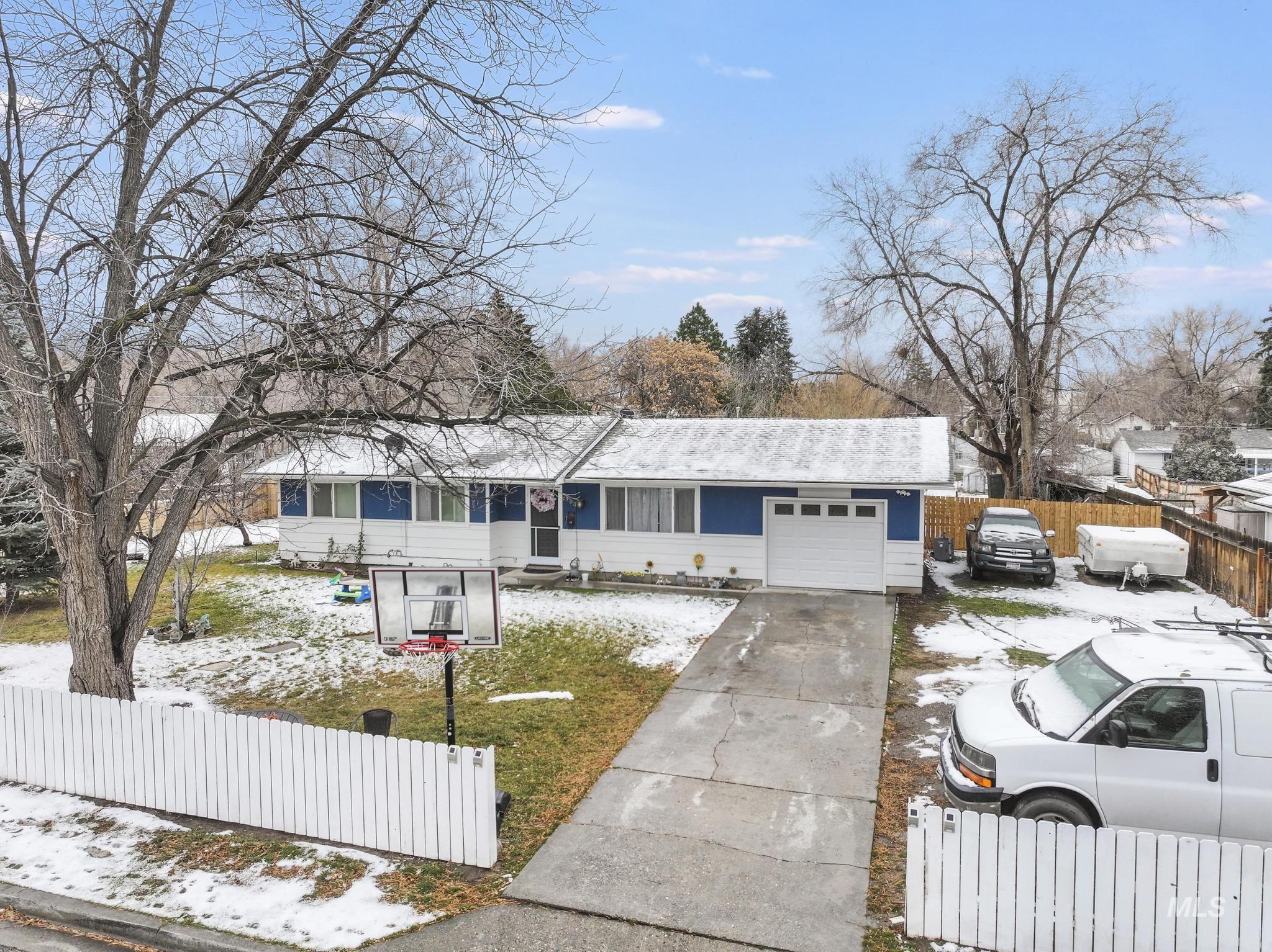 Ranch-style home with a fenced front yard, driveway, and an attached garage
