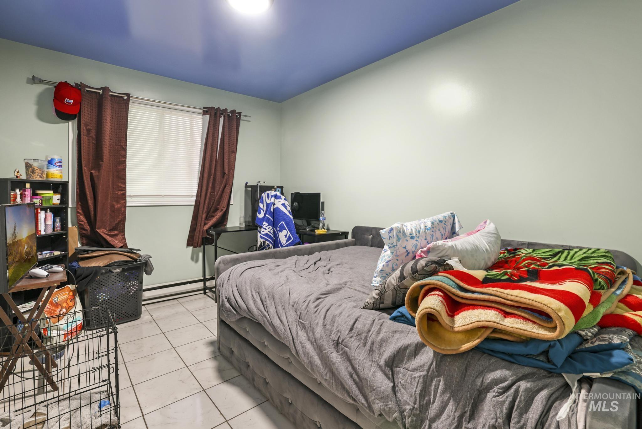 Bedroom with a baseboard heating unit and tile patterned floors
