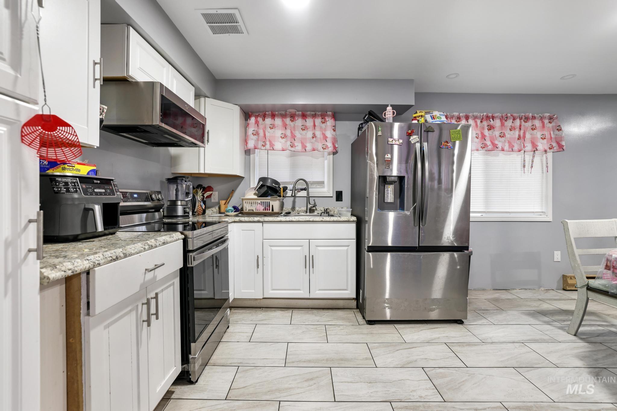 Kitchen featuring appliances with stainless steel finishes and white cabinetry