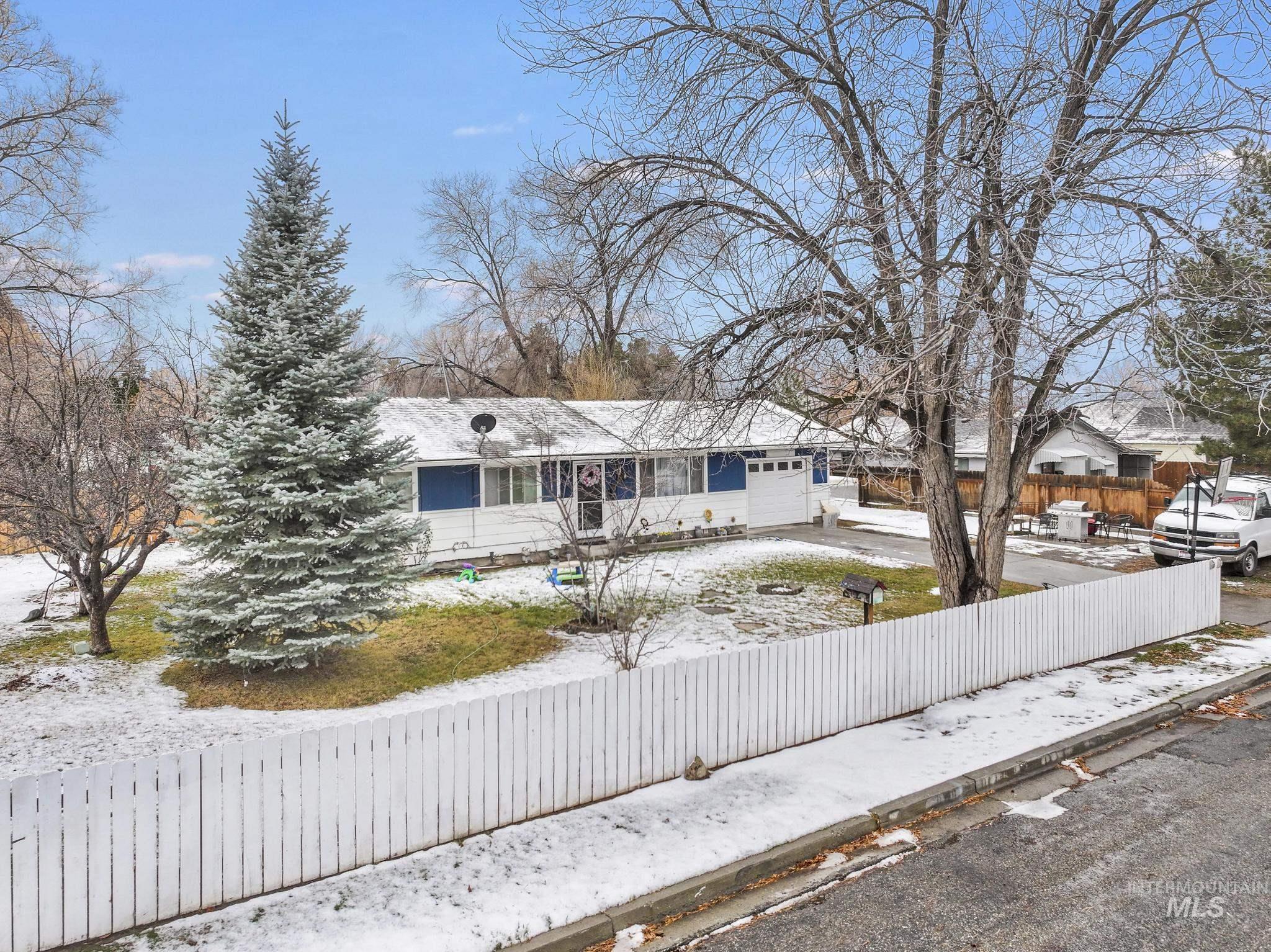 Ranch-style home featuring a fenced front yard, a garage, and driveway