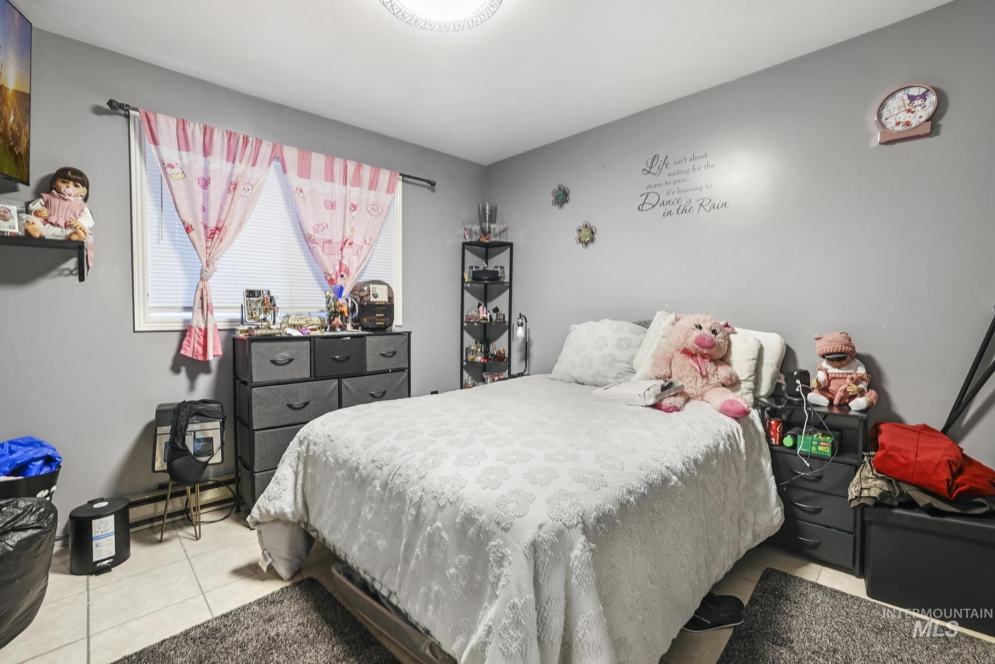 Bedroom featuring light tile patterned flooring and a baseboard radiator