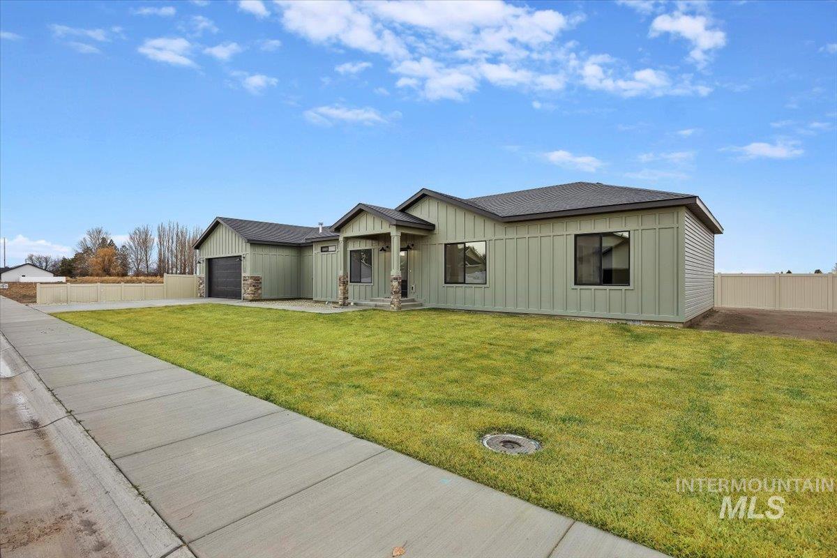 View of front of property featuring board and batten siding, a garage, and driveway