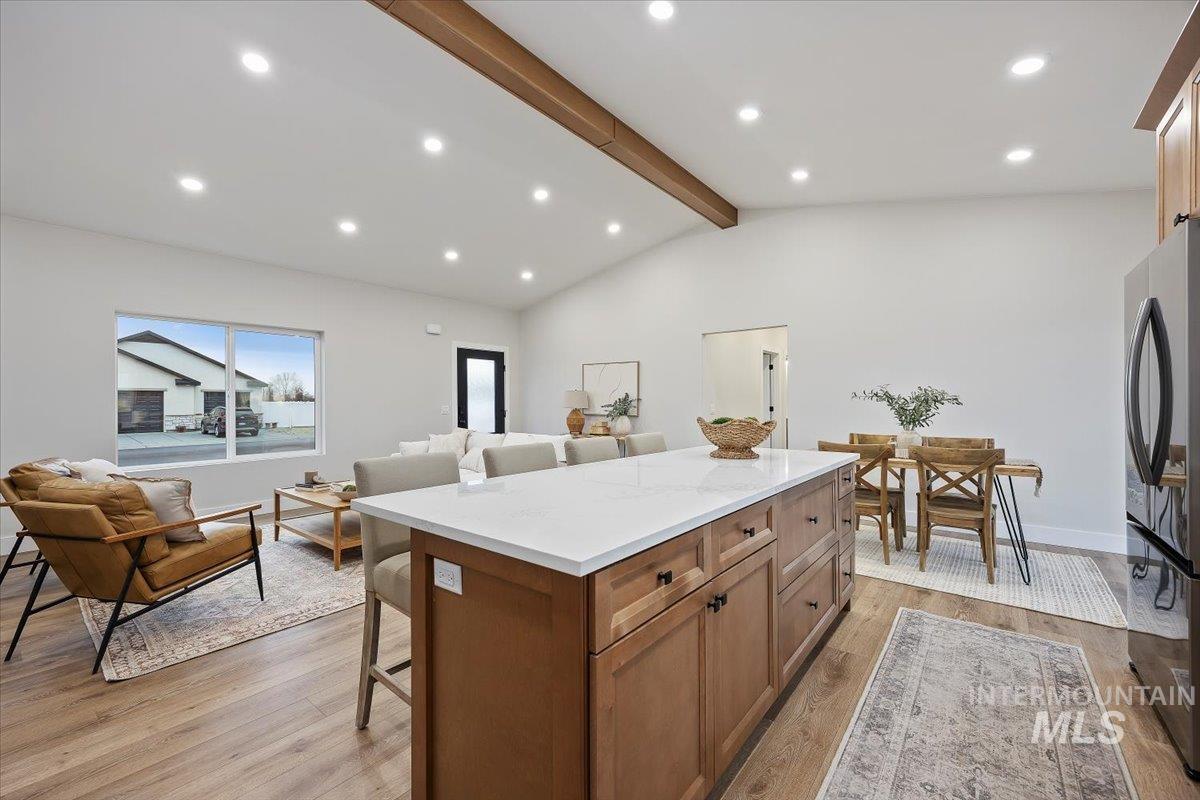 Kitchen featuring brown cabinetry, a breakfast bar area, recessed lighting, freestanding refrigerator, and light wood-style flooring