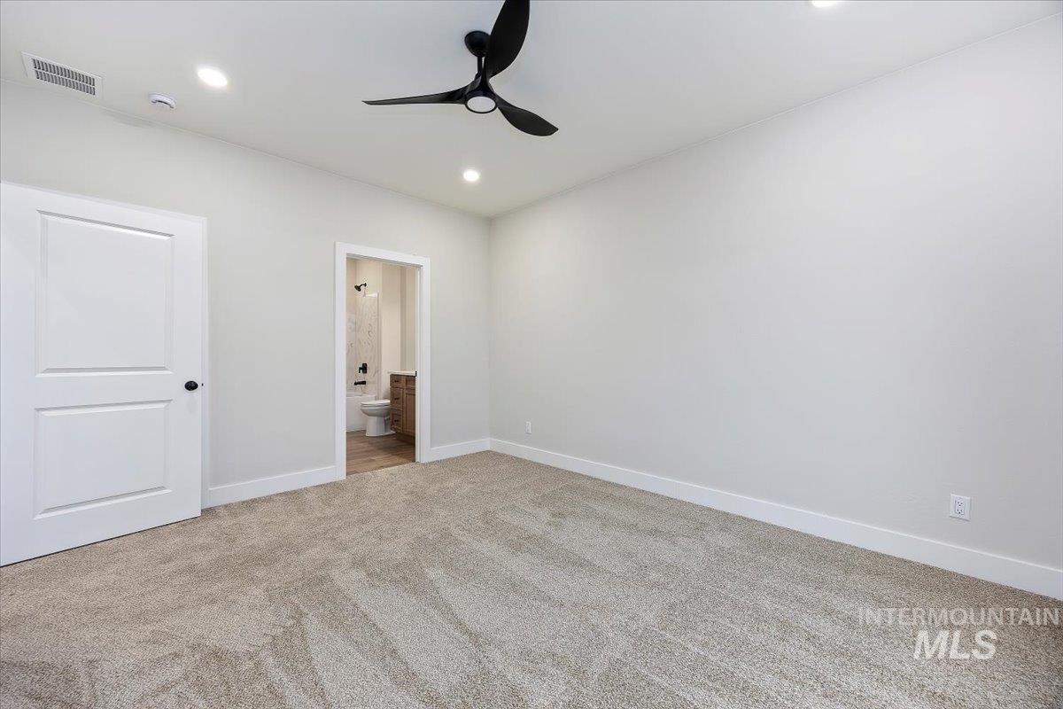 Unfurnished bedroom featuring ensuite bathroom, light carpet, ceiling fan, and recessed lighting