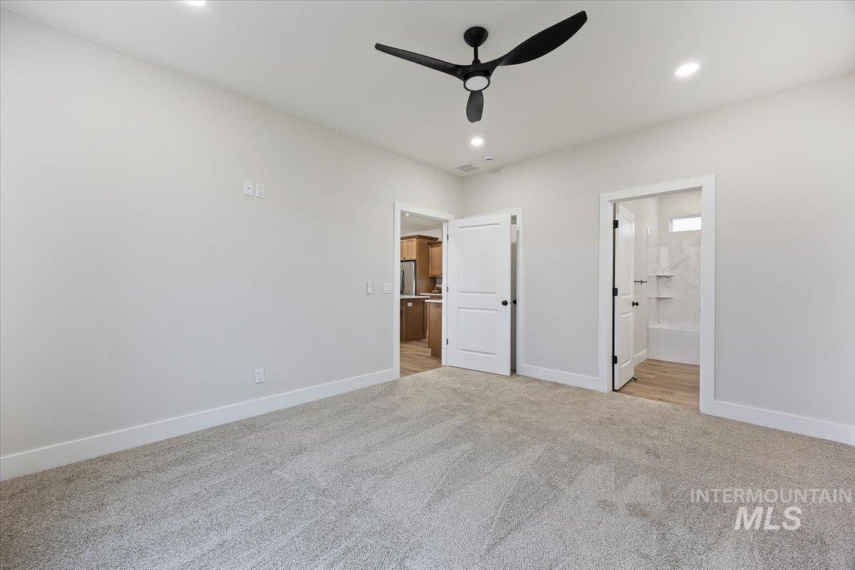Unfurnished bedroom with light colored carpet, a ceiling fan, ensuite bathroom, and recessed lighting