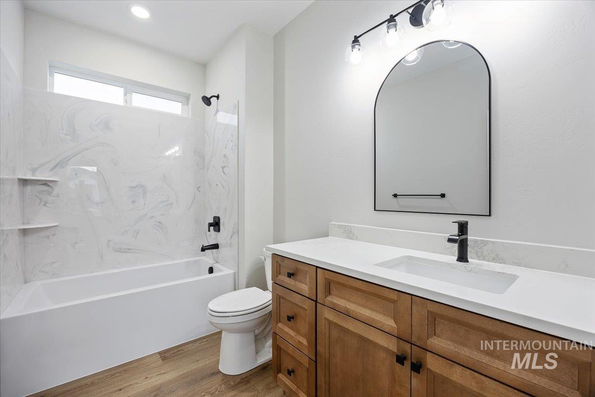 Bathroom with vanity, bathing tub / shower combination, and light wood-style flooring