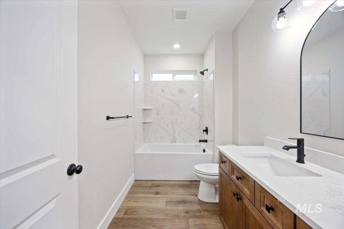 Full bath with vanity, light wood-style floors, and shower / bathtub combination