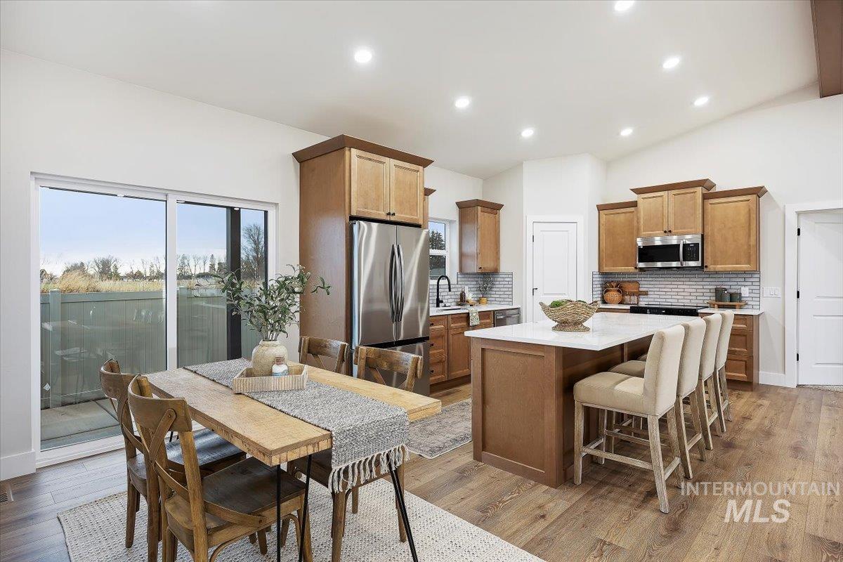 Kitchen featuring vaulted ceiling, stainless steel appliances, decorative backsplash, a breakfast bar, and a center island