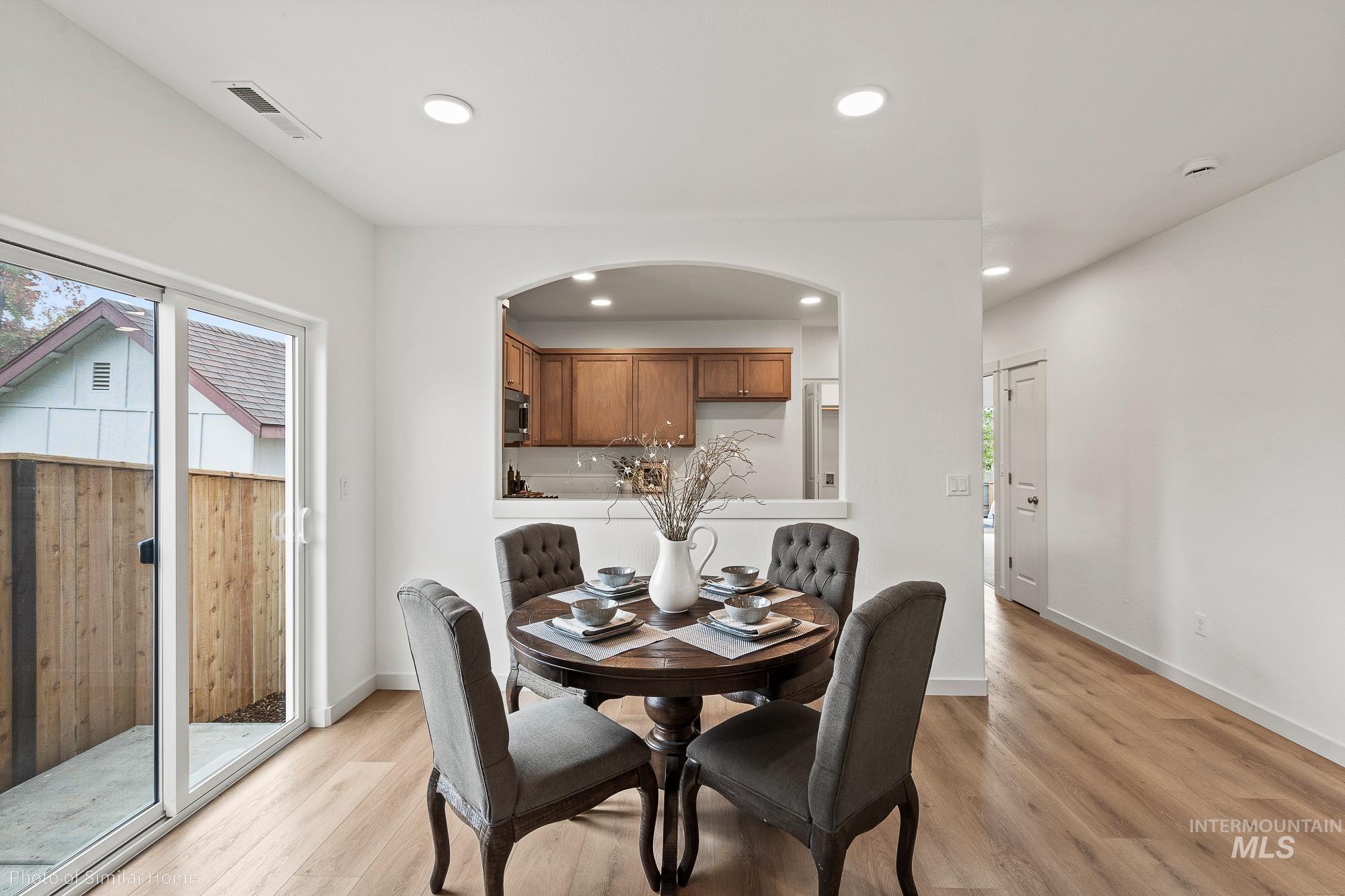 Dining area featuring light wood-style floors, recessed lighting, and arched walkways