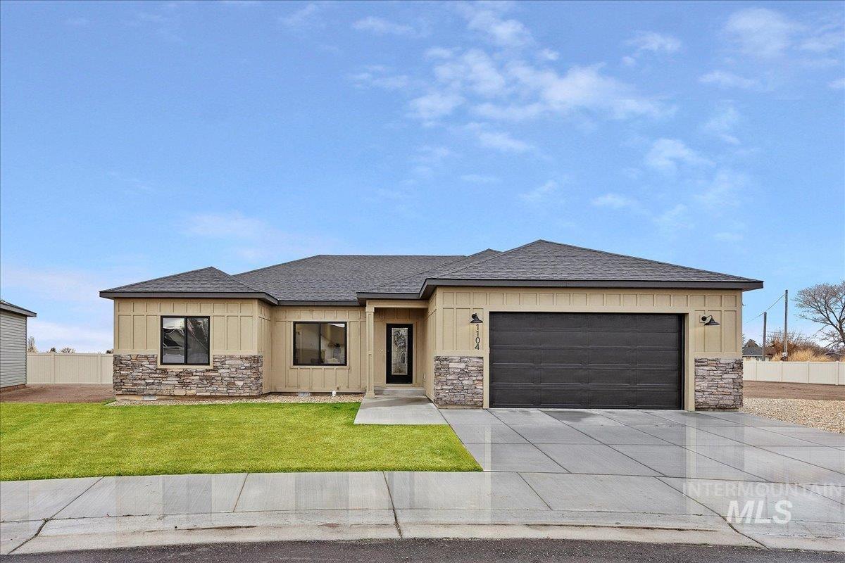 View of front facade with stone siding, board and batten siding, roof with shingles, and concrete driveway
