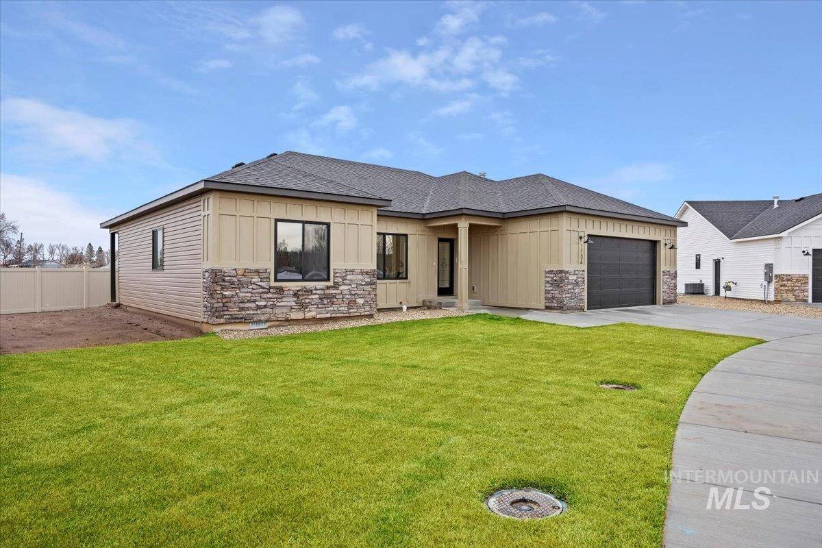 View of front of house with board and batten siding, stone siding, a shingled roof, a garage, and driveway
