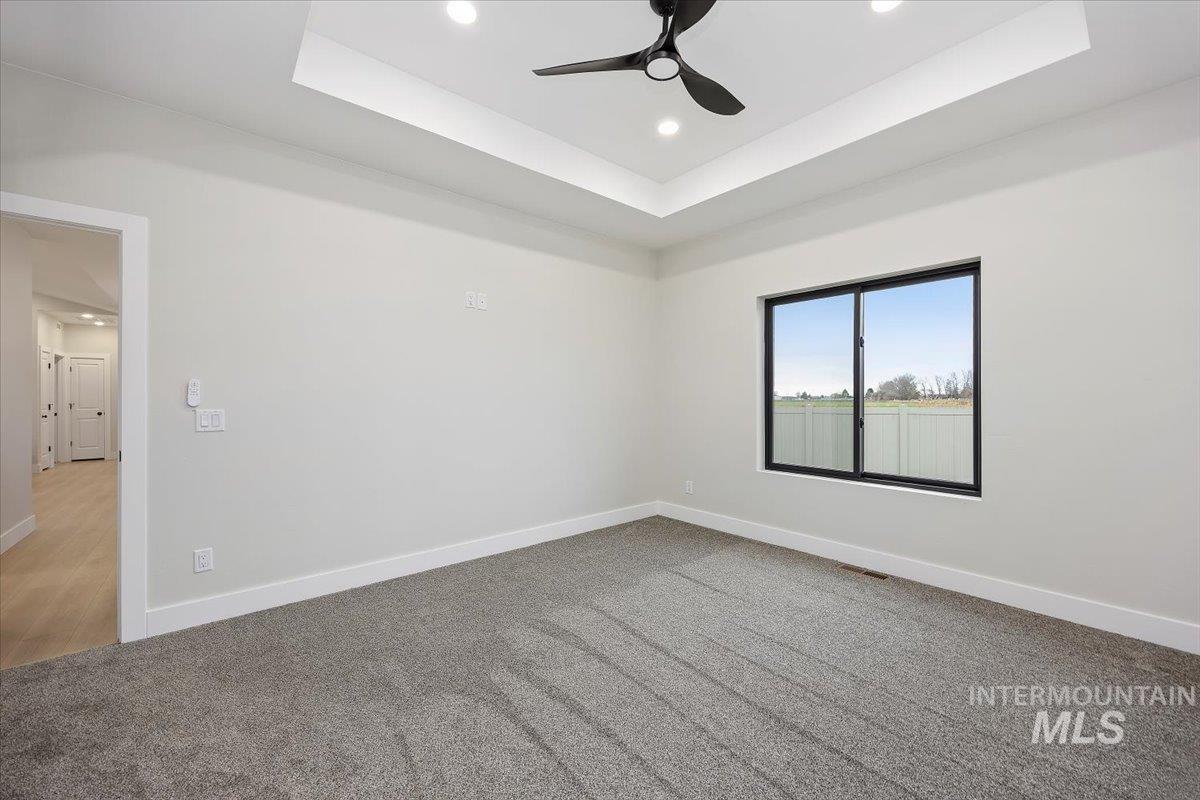 Spare room with a tray ceiling, ceiling fan, recessed lighting, and light carpet