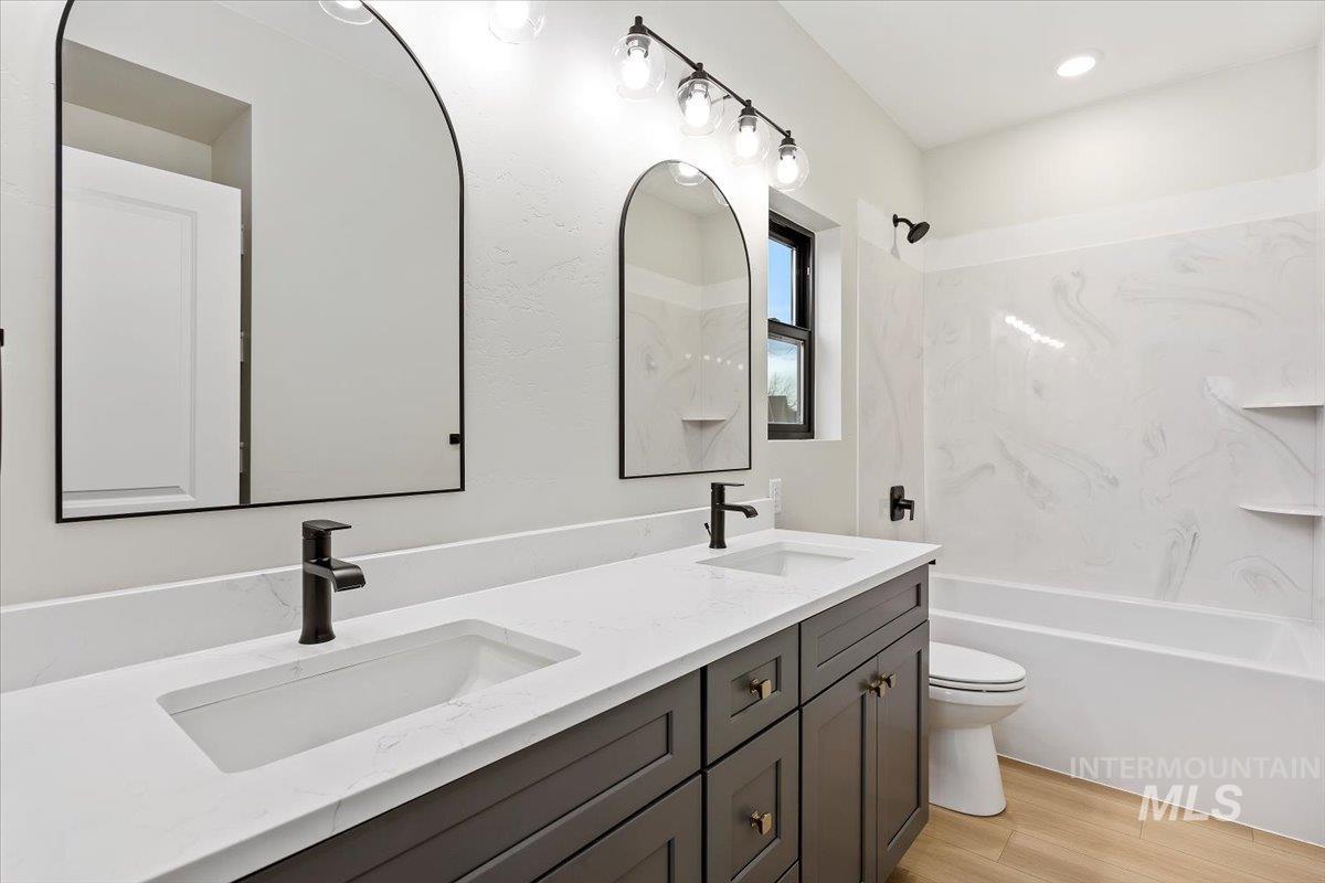 Full bath featuring double vanity, light wood-style floors, and shower / washtub combination