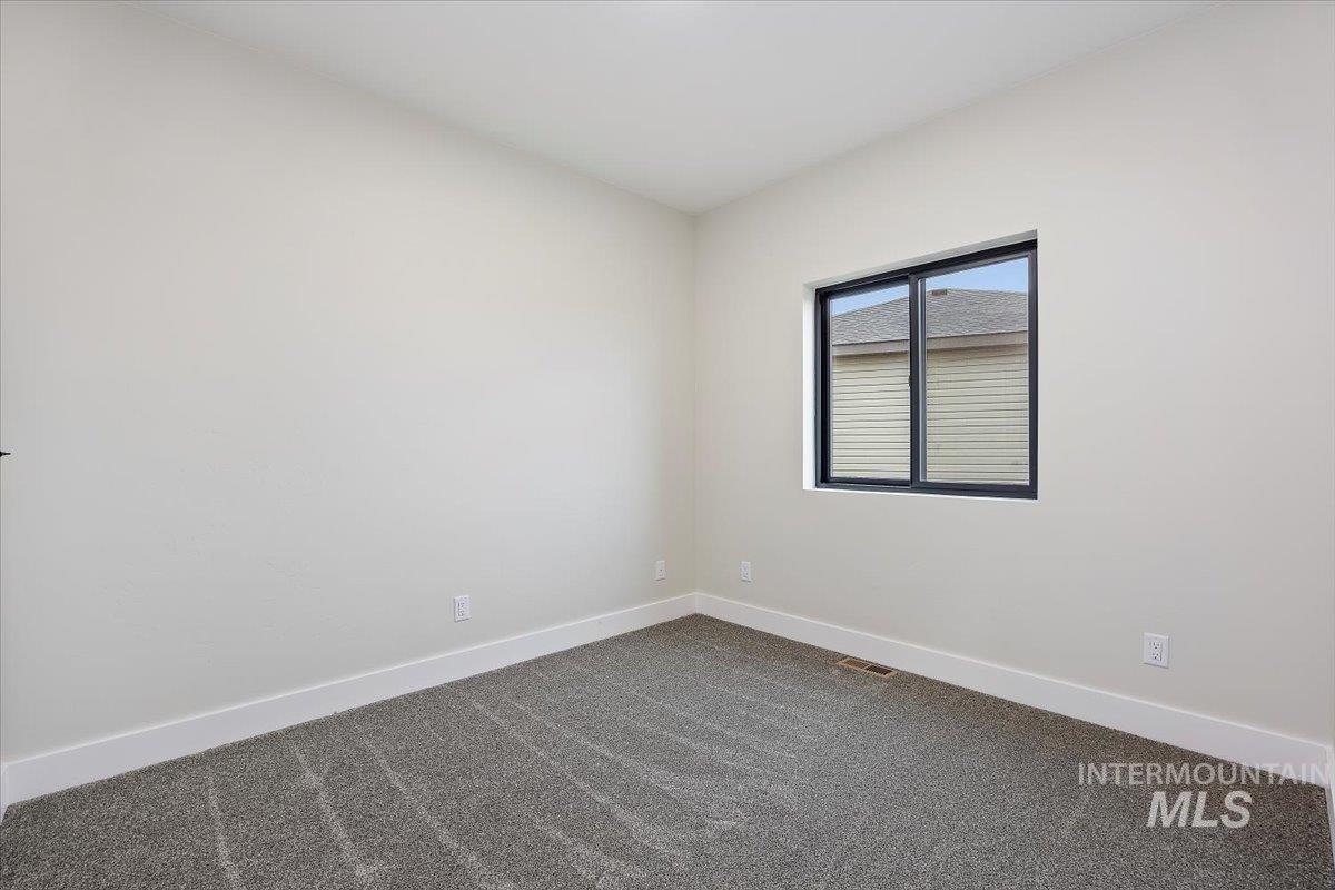 Unfurnished room with baseboards and dark carpet