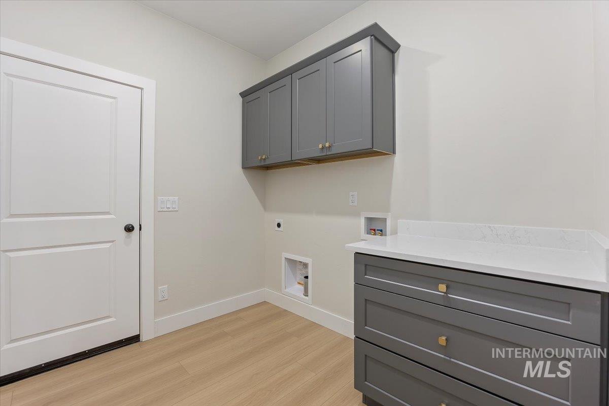 Washroom featuring washer hookup, cabinet space, light wood-style flooring, and hookup for an electric dryer