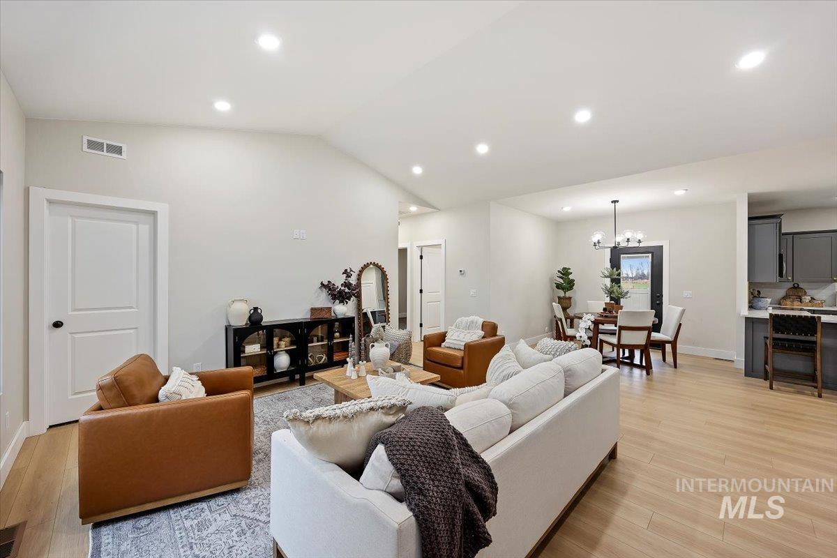 Living room with vaulted ceiling, light wood-type flooring, recessed lighting, and a chandelier