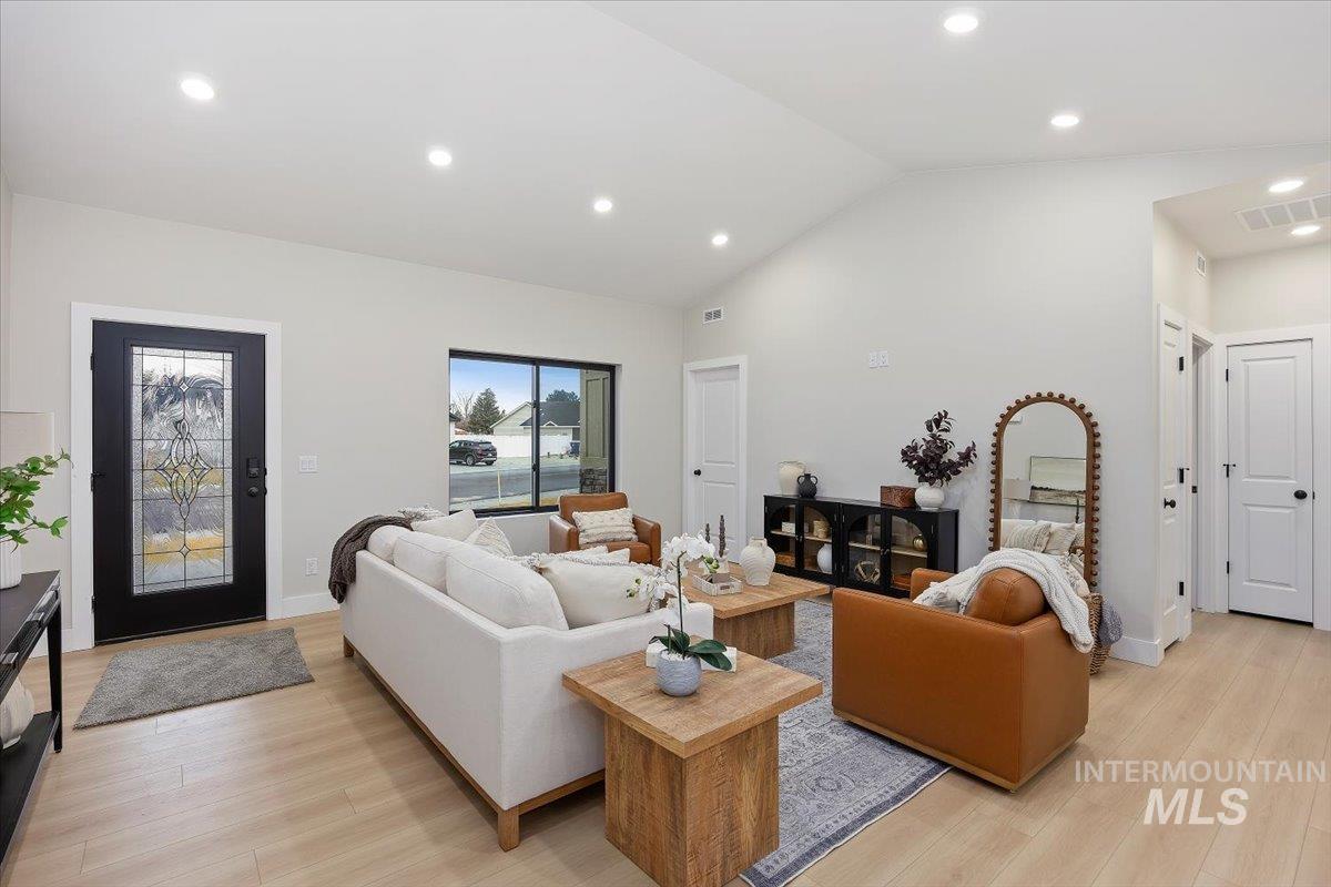 Living room with recessed lighting, light wood-style floors, and high vaulted ceiling