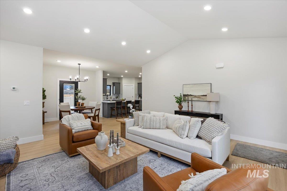 Living area with recessed lighting, light wood finished floors, vaulted ceiling, and a chandelier