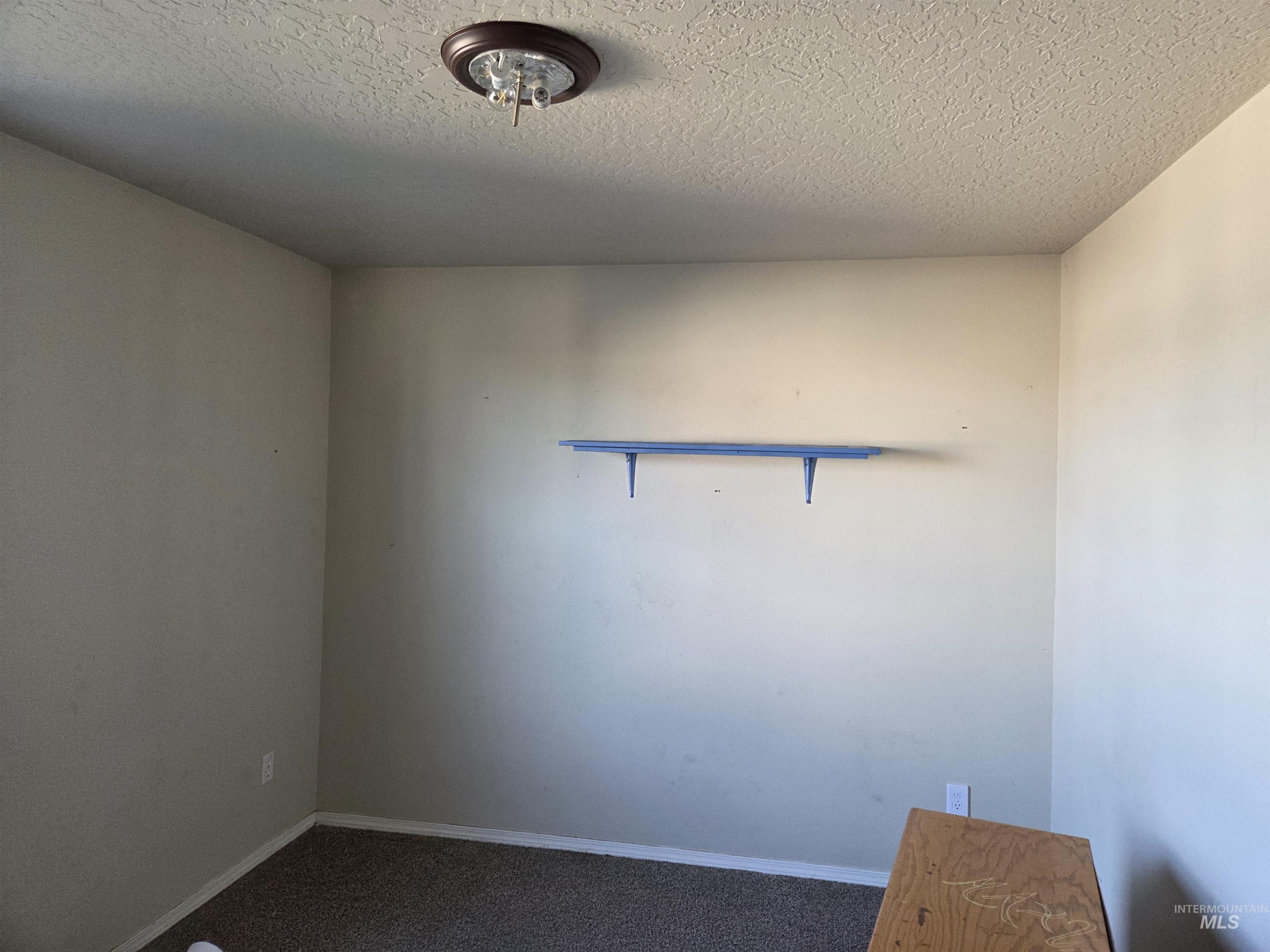 Unfurnished room featuring a textured ceiling and dark colored carpet