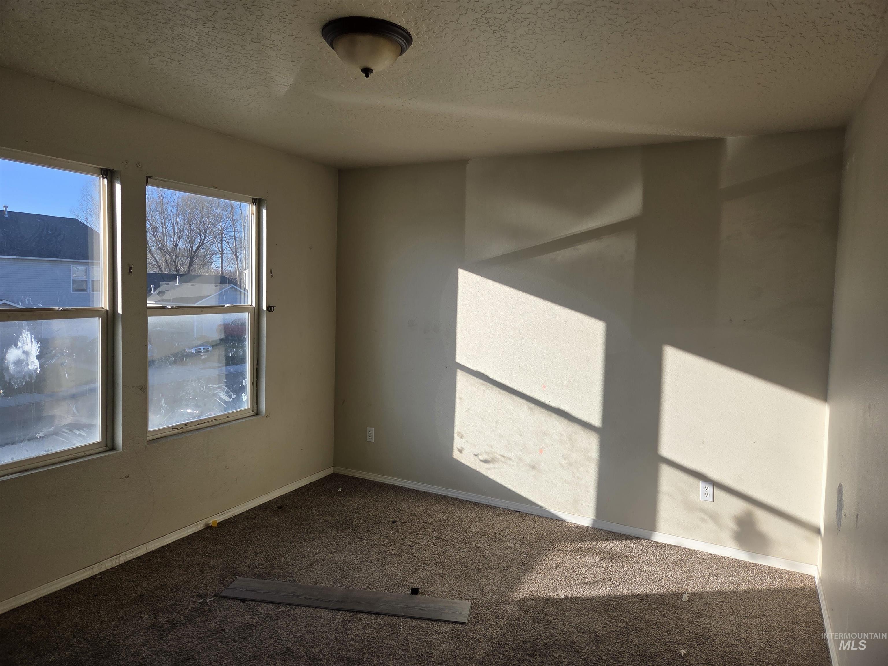 Carpeted spare room with a textured ceiling and baseboards