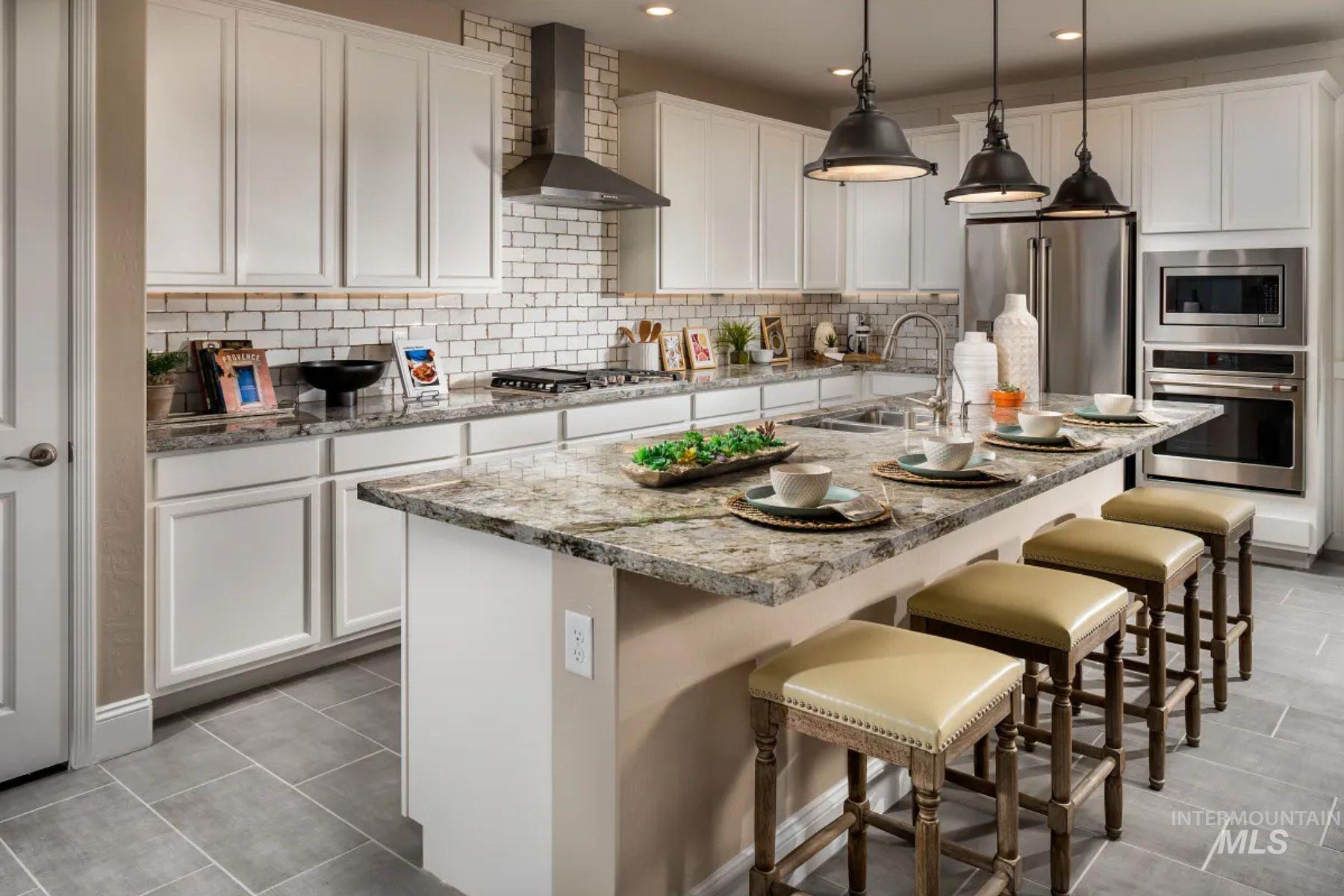 Kitchen featuring a breakfast bar area, wall chimney range hood, stainless steel appliances, an island with sink, and backsplash
