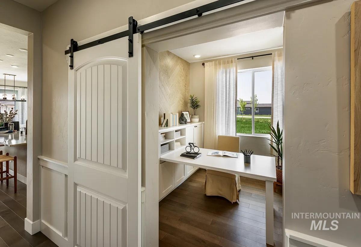 Office with a barn door and dark wood-type flooring