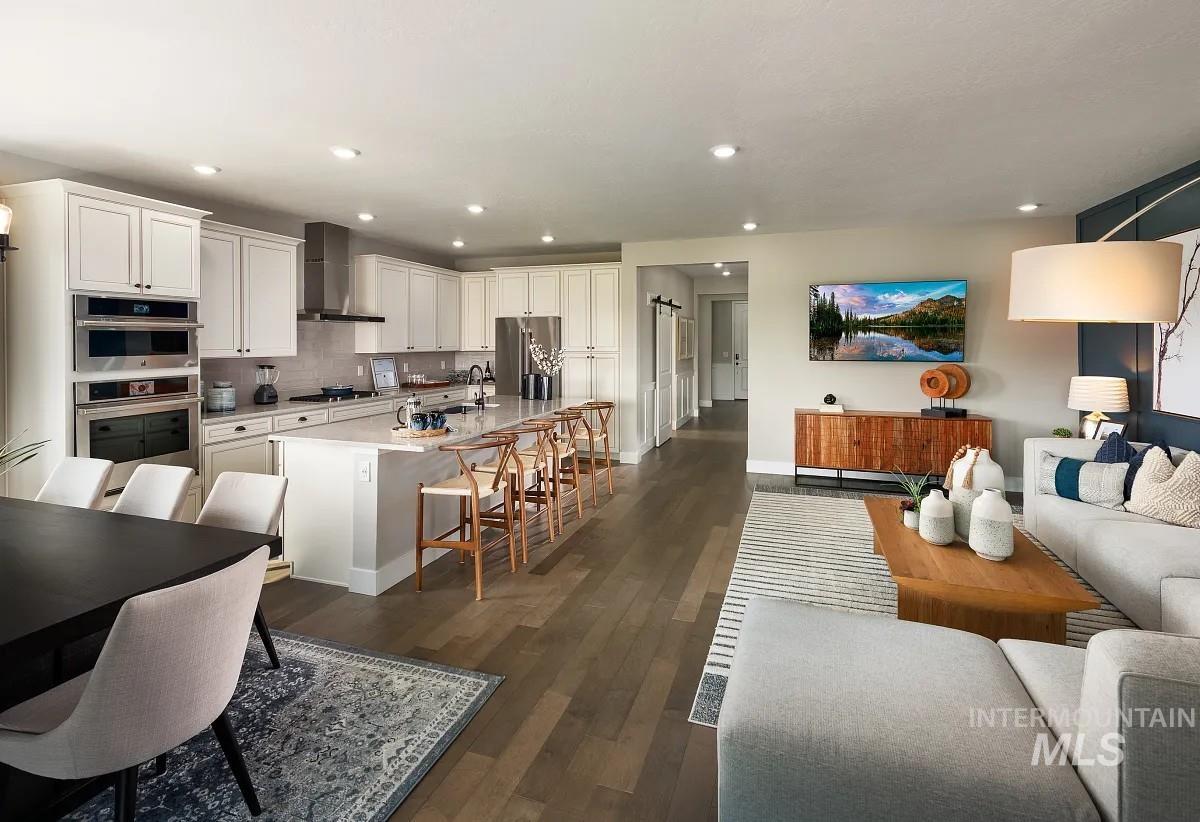 Kitchen featuring a breakfast bar, a center island with sink, stainless steel appliances, white cabinets, and open floor plan