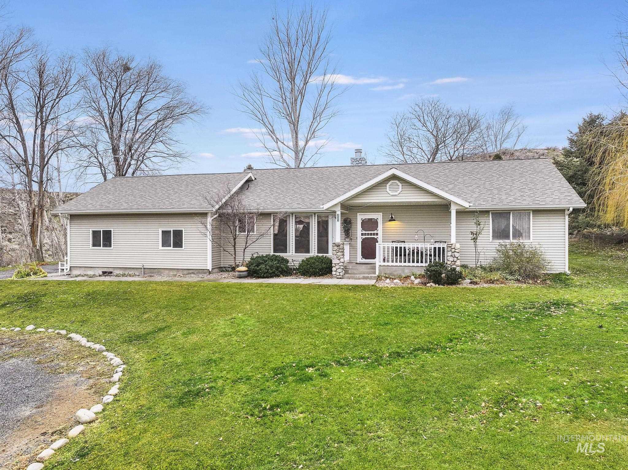 Ranch-style house with a porch, roof with shingles, a front lawn, and a chimney
