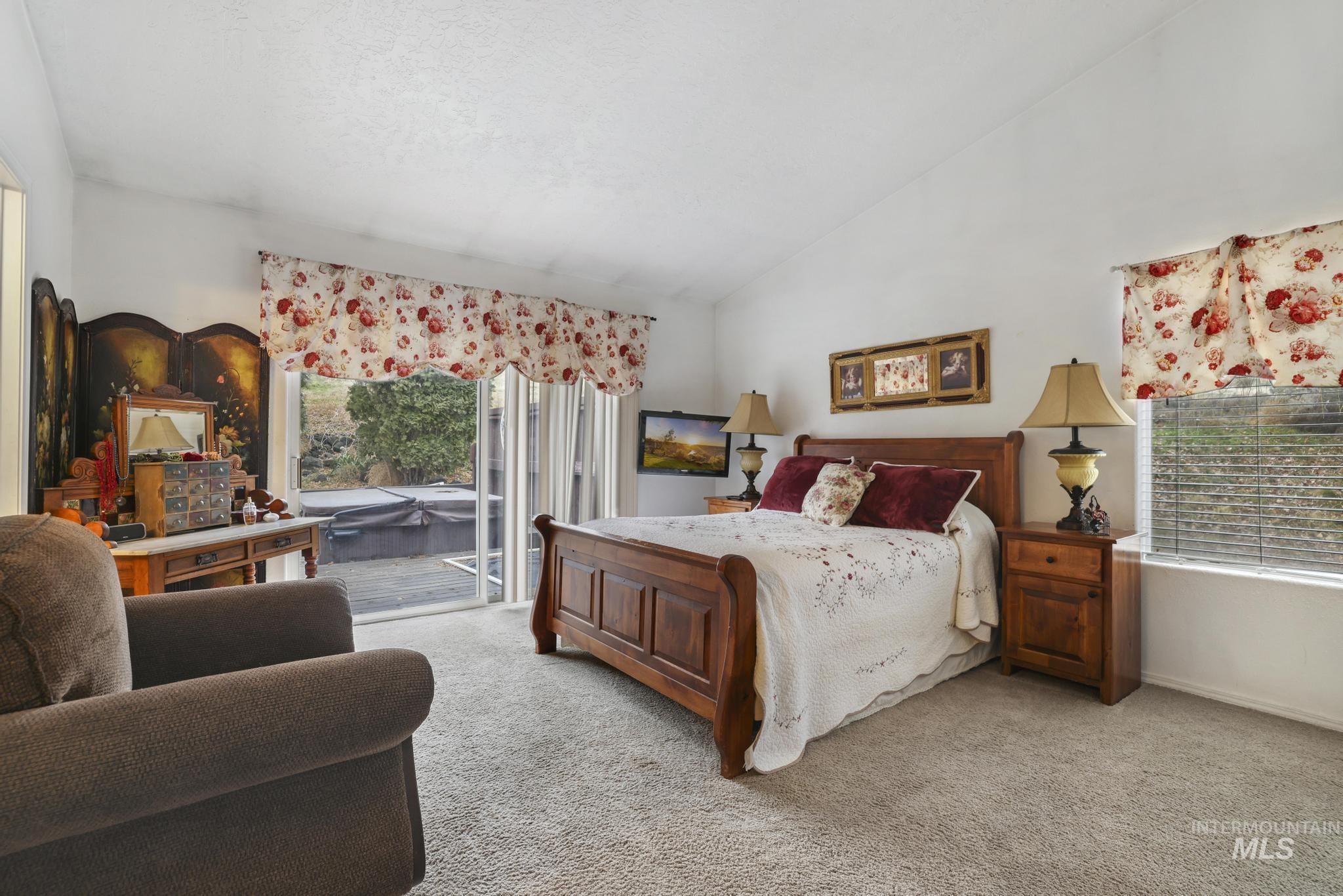 Bedroom with access to outside, lofted ceiling, multiple windows, and light colored carpet