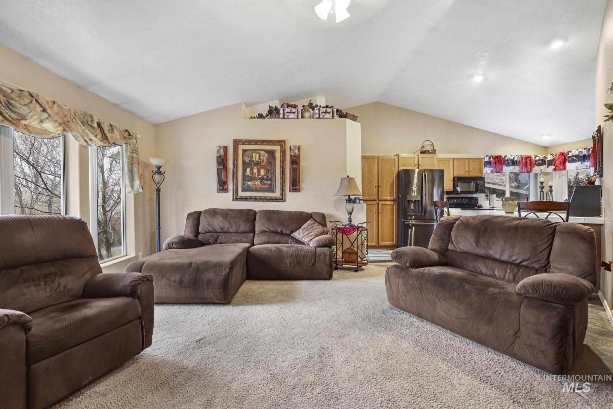 Carpeted living area featuring vaulted ceiling