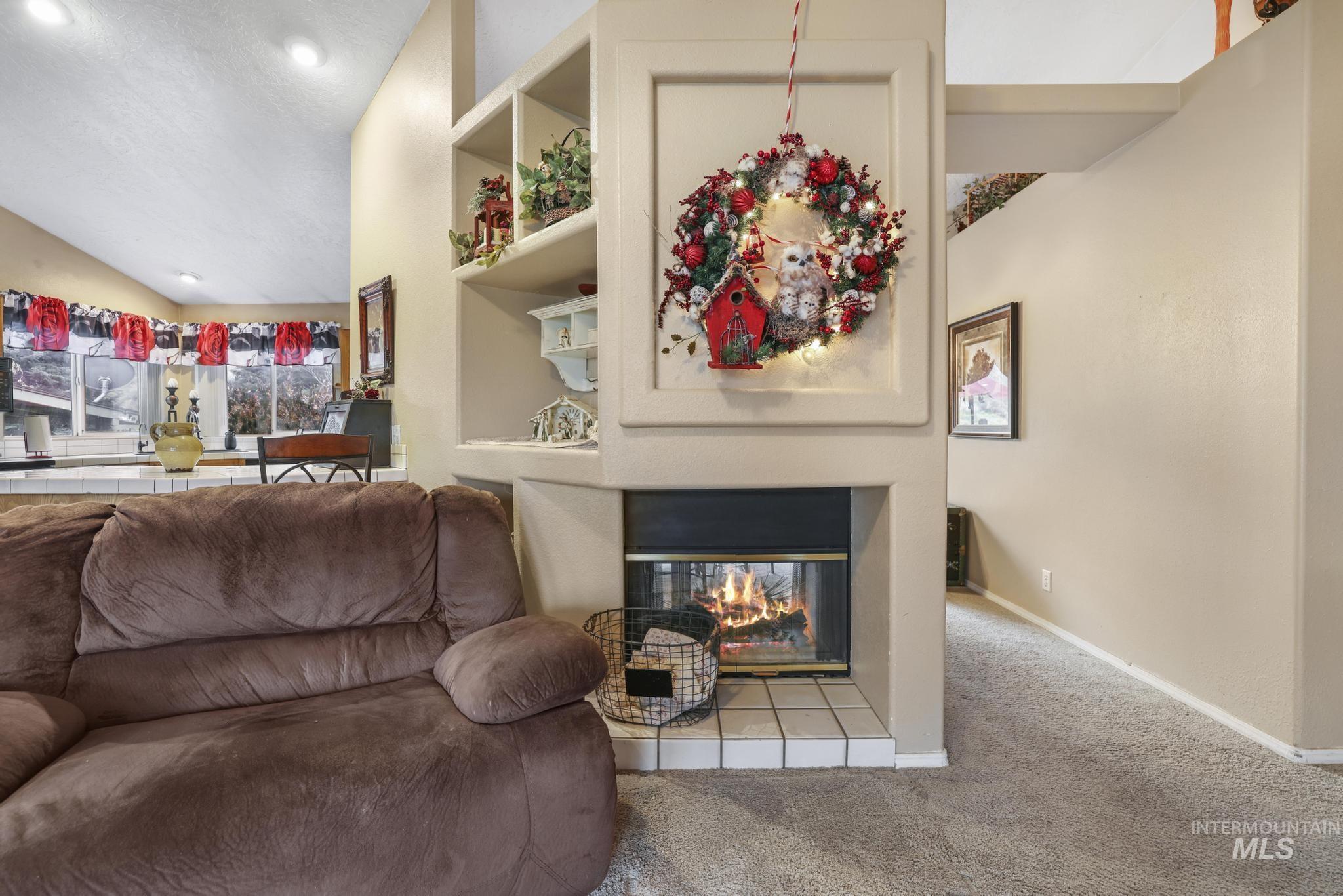 Living area featuring a multi sided fireplace, built in shelves, carpet floors, and vaulted ceiling