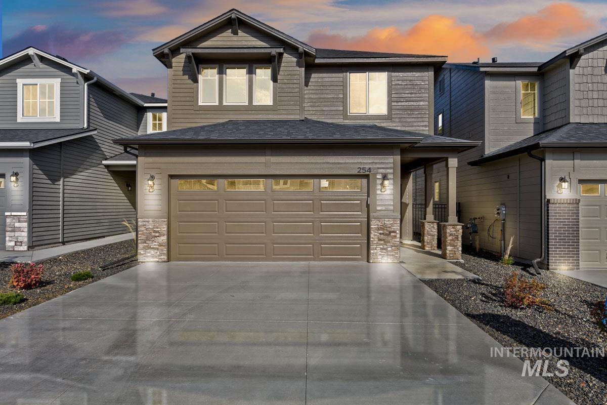 View of front facade with stone siding, concrete driveway, and an attached garage