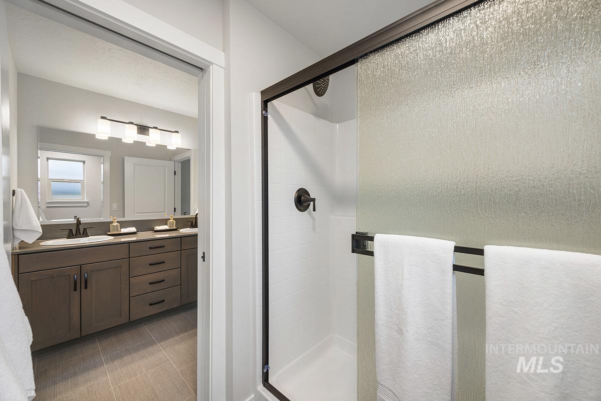 Bathroom featuring a shower stall, vanity, and light tile patterned flooring
