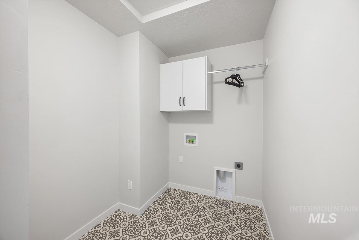 Laundry area with a textured ceiling, hookup for an electric dryer, hookup for a washing machine, and cabinet space