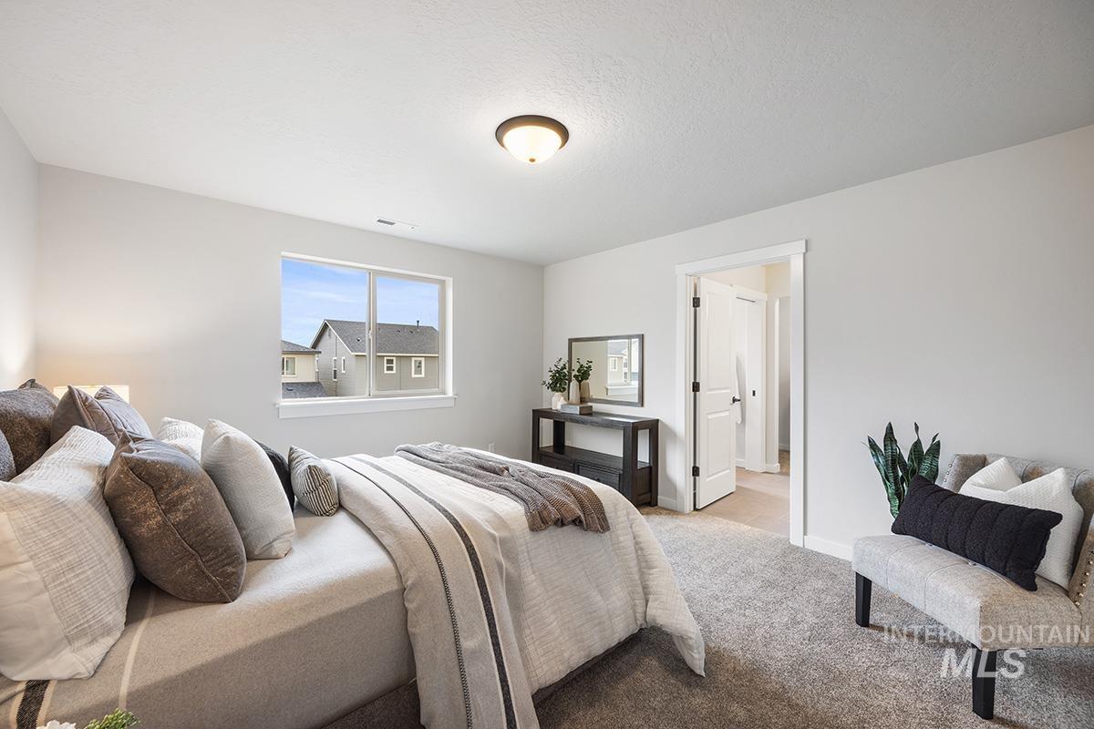 Carpeted bedroom featuring baseboards and a textured ceiling