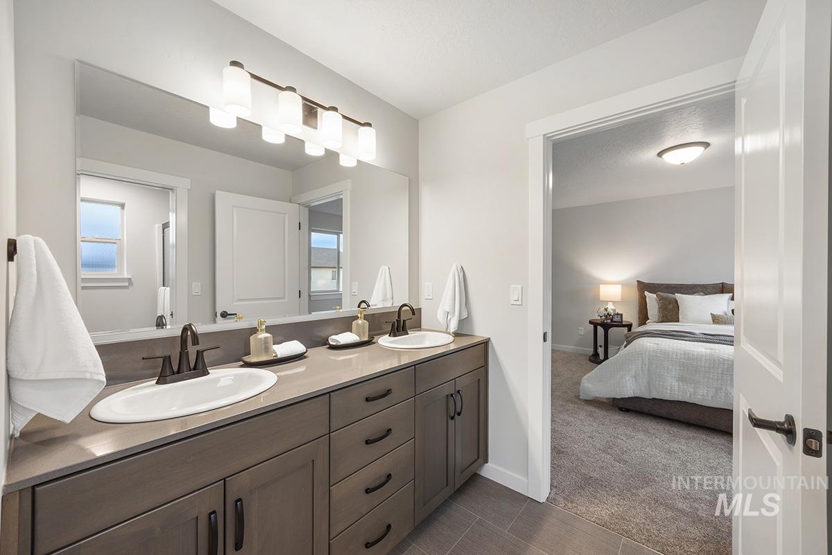 Full bathroom with dark carpet, double vanity, ensuite bathroom, and dark tile patterned flooring