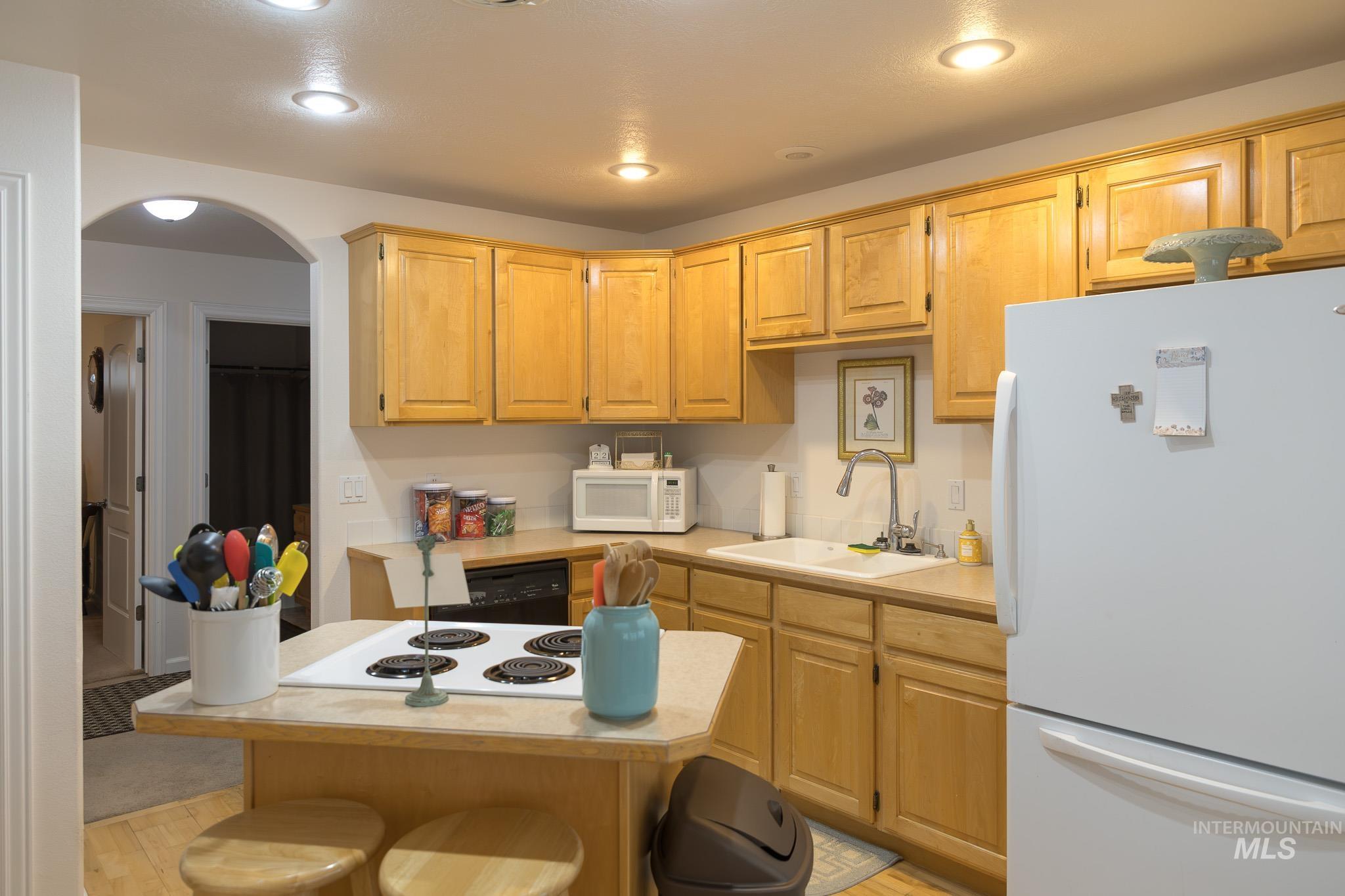 Kitchen with white appliances, light countertops, a breakfast bar, a center island, and recessed lighting