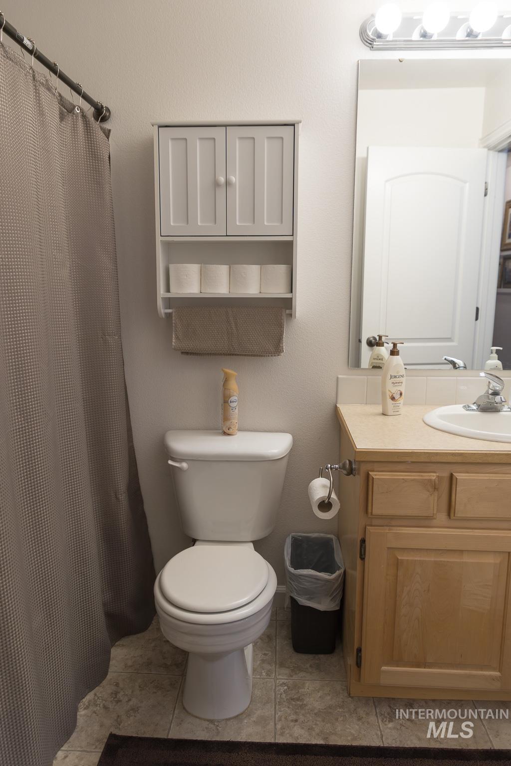Bathroom with curtained shower, vanity, and light tile patterned floors